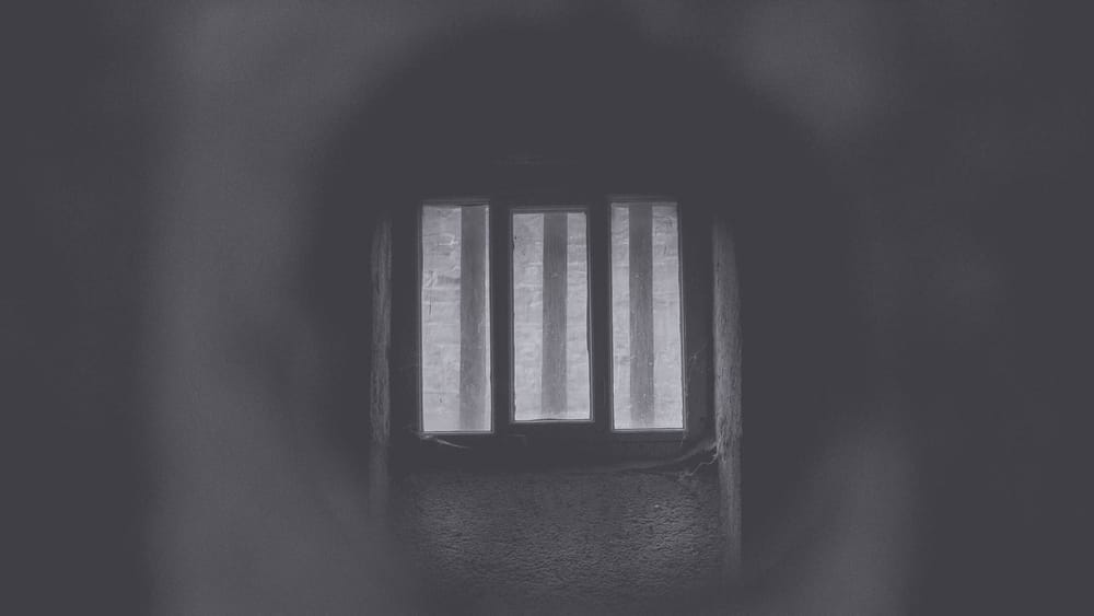 A dark tunnel with prison bars in sight.